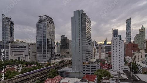 Time lapse view of Bangkok cityscape with high-rise buildings and BTS skytrains with moving clouds photo