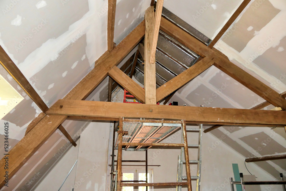 Obraz premium Plasterboard fitted over new roof insulation highlighting exposed beams and trusses