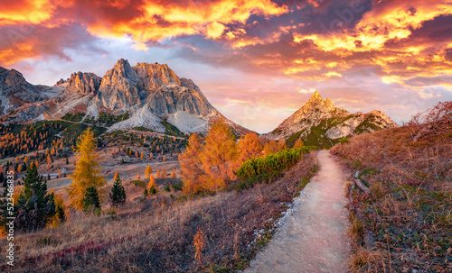 Fiery clouds over the trek to Falzarego pass. Majestic autumn view of Forcella and Sass de Stria peaks. Fantastic sunrise in Dolomite Alps, Cortina d'Ampezzo lacattion, Italy, Europe. photo