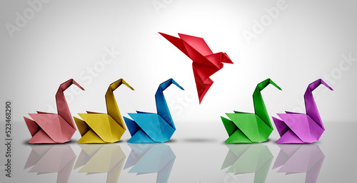 Innovative thinker concept and new idea thinking as a symbol of revolutionary innovation and inspiration metaphor as a group of paper swans and a game changer origami bird in flight.  photo