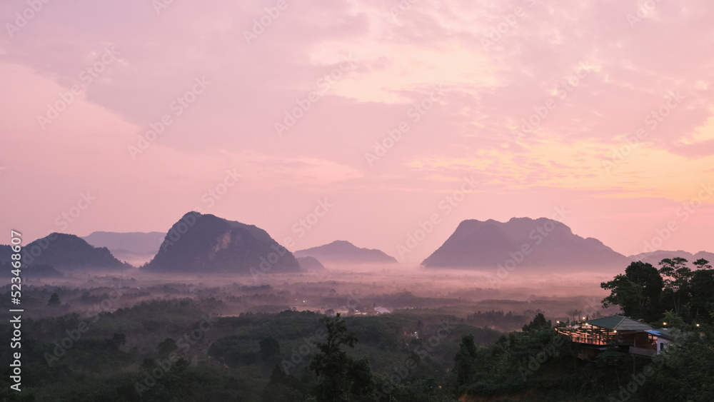 Panorama scenery of tranquil tropical natural landscape background in fog, view of green forest in a mountain range, in the dawn with sunrise, beautiful outdoor environment, Asia travel destination.