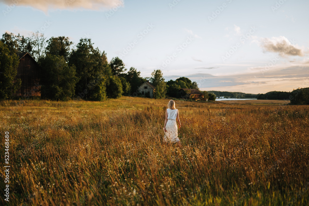 Obraz premium young woman standing in the countryside sunset