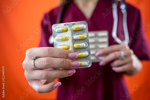 Young female doctor holding and showing natural healthy pills isolated on plain background.