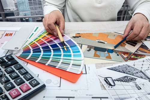 male  in the office selects a palette of colors for drawings of the house on the project.
