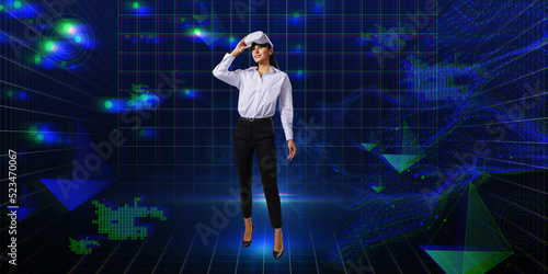 Thoughtful young european businesswoman with VR glasses standing on creative glowing wide blue metaverse background. Cyberspace, augmented reality, future and technology concept.