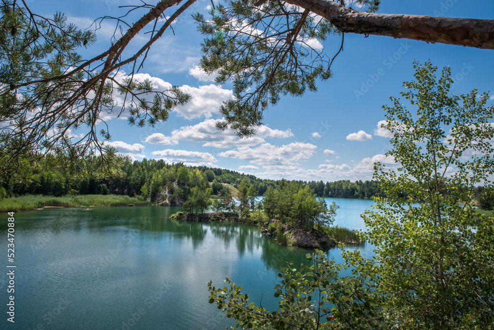 A rocky, tree-covered island in a blue-green lake where there was a granite quarry