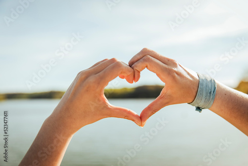 Young woman making heart shape on sunny day