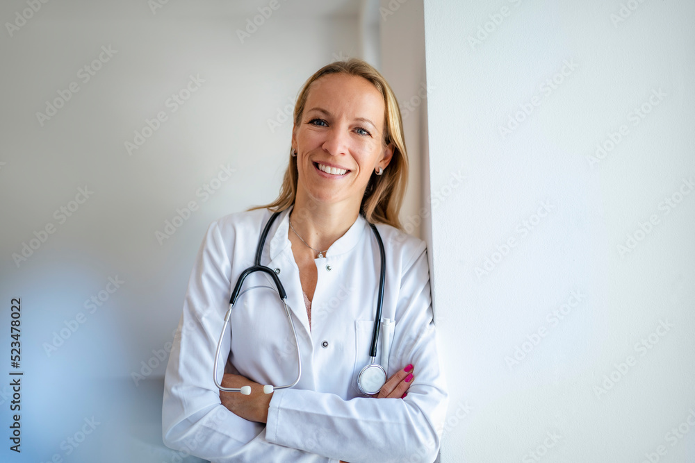 Portrait of smiling female doctor leaning against a wall Portrait of smiling female doctor leaning against a wall