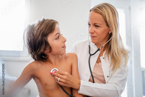 Female doctor with stethoscope examining boy photo