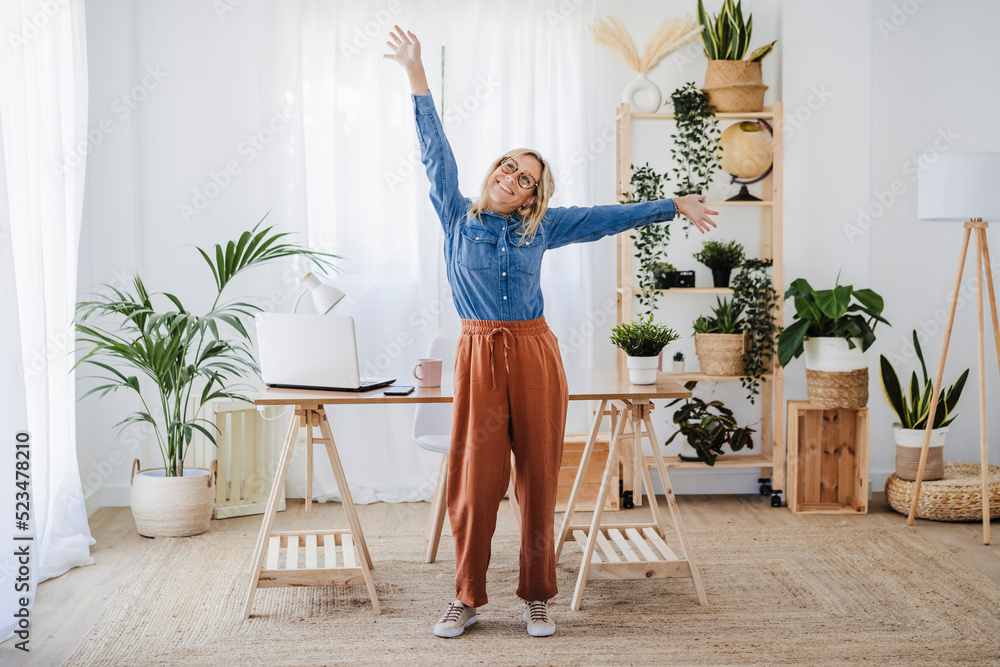 Happy freelancer with arms raised standing at home office Happy freelancer with arms raised standing at home office