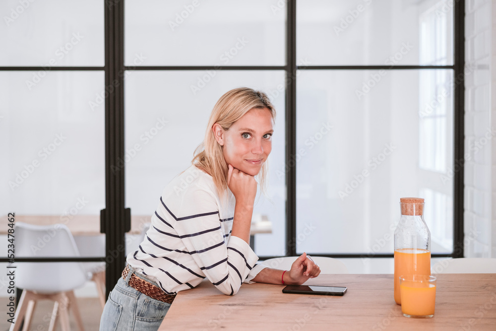 Young woman leaning on kitchen counter at home Young woman leaning on kitchen counter at home