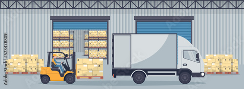 Industrial warehouse for the storage of products with metal racks and shelves for pallet support. Forklift trucks unloading from refrigerated truck. Industrial storage and distribution of products