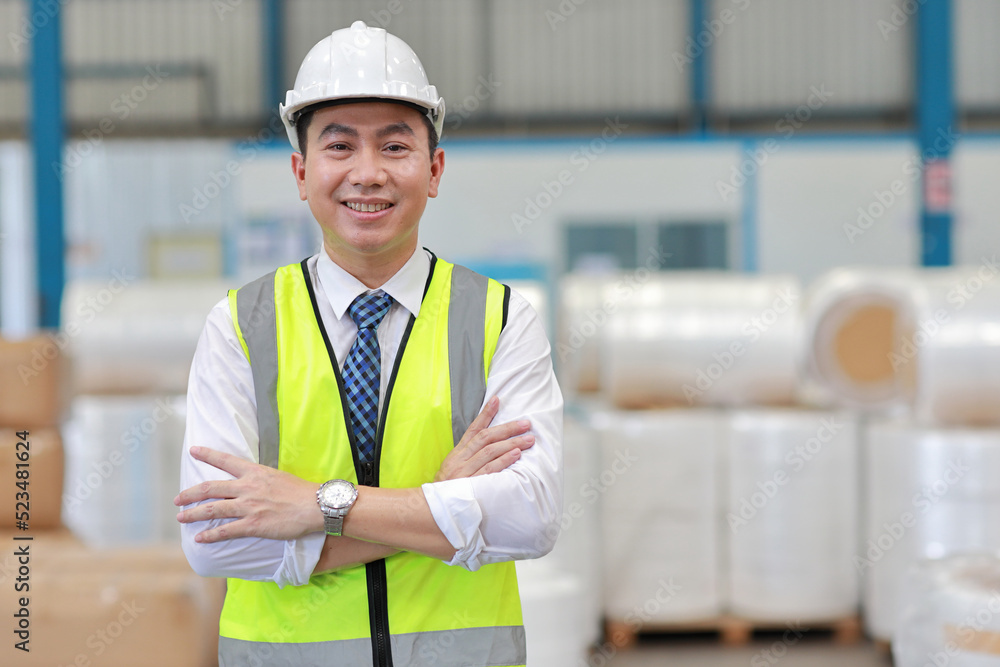 Asian engineering worker man portrait standing and arm crossed with happy smiling face with confident and blurred large warehouse background Asian engineering worker man portrait standing and arm crossed with happy smiling face with confident and blurred large warehouse background