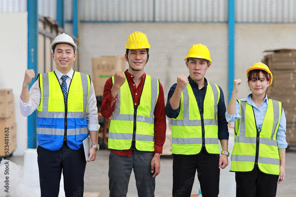 Group of technician engineer and businessman in protective uniform with hardhat standing and raising hands celebrate successful together or completed deal commitment at industry manufacturing factory Group of technician engineer and businessman in protective uniform with hardhat standing and raising hands celebrate successful together or completed deal commitment at industry manufacturing factory