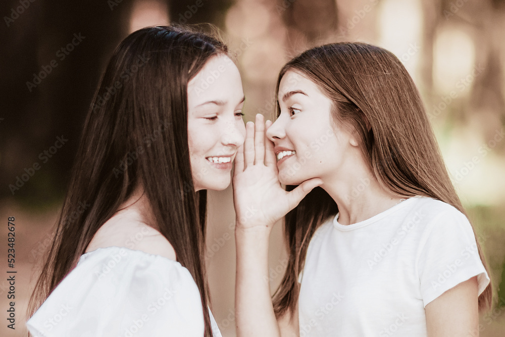 Two girlfriends whisper in the summer forest. Close-up Two girlfriends whisper in the summer forest. Close-up