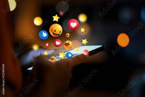 Woman using smartphone at night and social 3D graphics icon on screen with beautiful bokeh. girl's hand using a smartphone social icons on smartphone screen