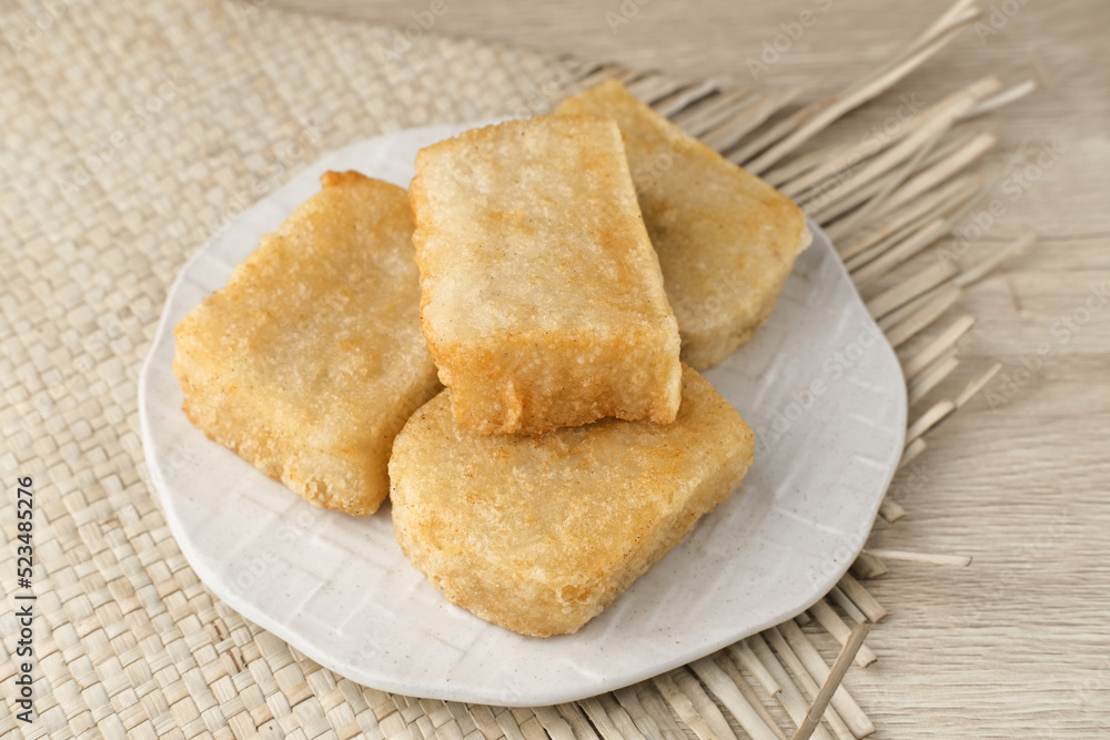 Jadah Goreng or Fried sticky rice cake is Javanese traditional cake made from glutinous rice and grated coconut. Served in white plate, selective focus image.
