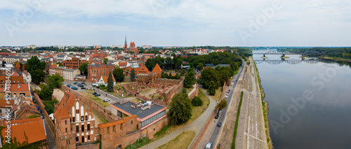 Toruń, promenada nad rzeką Wisła, widok w kierunku wschodnim na średniowieczną część miasta i most kolejowy
