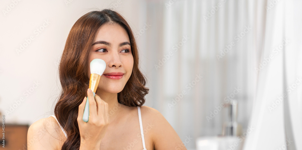 Smiling of young beautiful pretty asian woman clean fresh healthy white skin.asian girl holding make-up brushes and make up on face with cosmetics set at home.facial beauty Smiling of young beautiful pretty asian woman clean fresh healthy white skin.asian girl holding make-up brushes and make up on face with cosmetics set at home.facial beauty