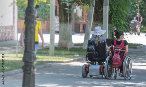 Two disabled person on an electric wheelchair on a city street . © bborriss