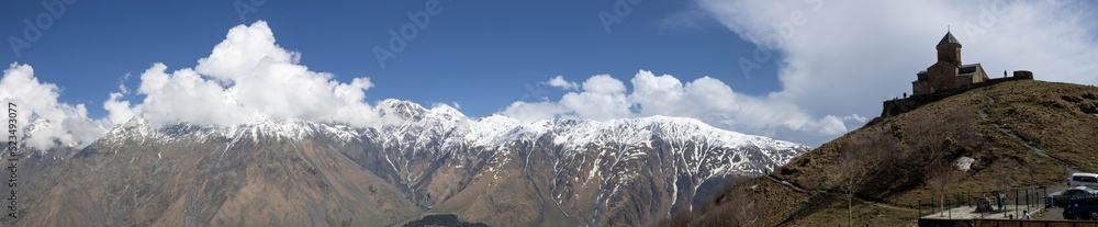 A scenic panoramic view of the Gergeti Trinity Church and Caucasus Mountains