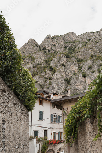 Rustic Italian architecture. Italian village in mountains with traditional buildings, wooden windows, flowers and blooming trees. Aesthetic summer vacation travel concept