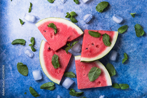 Sliced watermelon on an old blue background with mint and ice