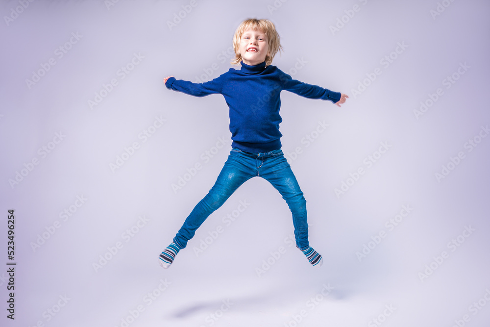 Funny little boy jumping. Hands and feet apart. In a studio