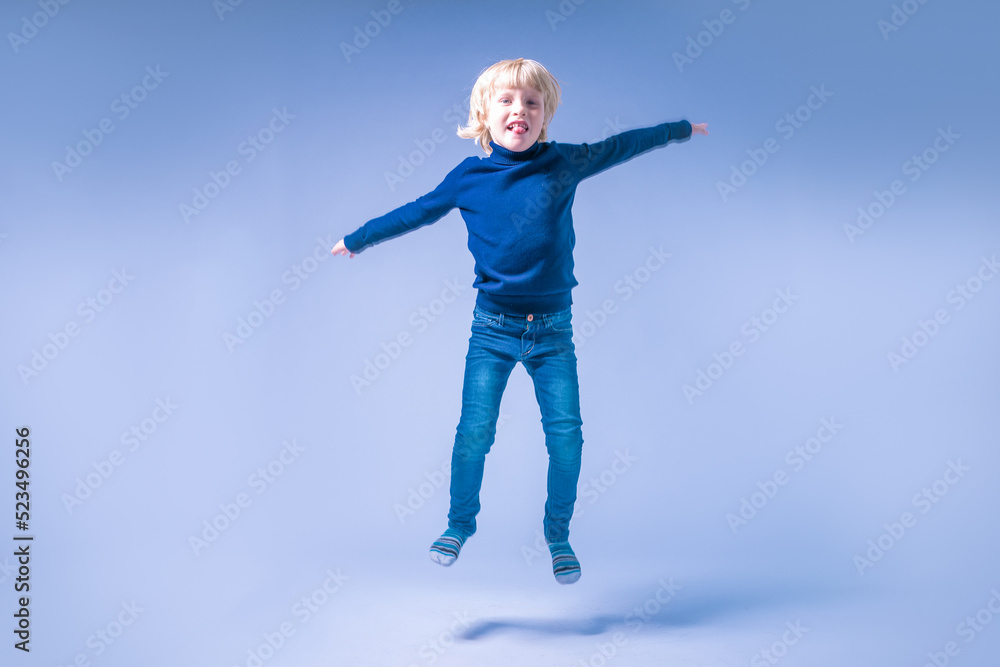 Funny little boy jumping. Hands and feet apart. In a studio Funny little boy jumping. Hands and feet apart. In a studio