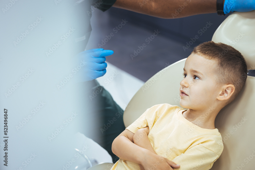 Dentist examining little boy's teeth in clinic. Funny Little Boy Smiles in a Dental Clinic. Work of a Dentist with Children. Healthcare and Medicine Concept. Little boy at regular dental check-up Dentist examining little boy's teeth in clinic. Funny Little Boy Smiles in a Dental Clinic. Work of a Dentist with Children. Healthcare and Medicine Concept. Little boy at regular dental check-up