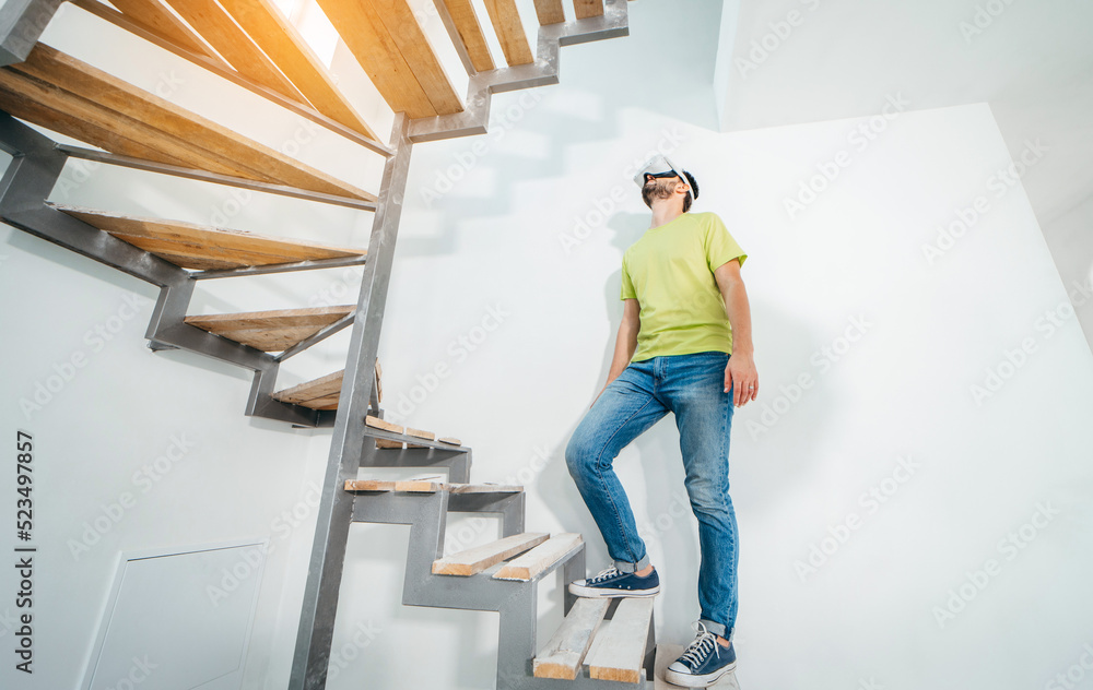 Young bearded man using virtual reality goggles before starting renovations in his townhouse