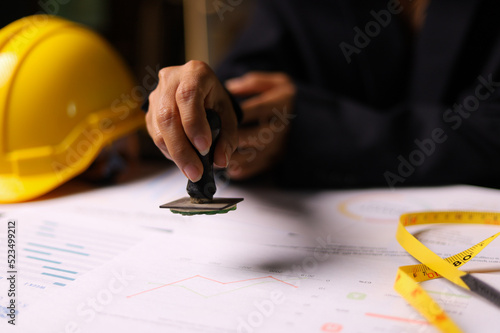 Close-up of a Construction supervision hand stamping document in the office