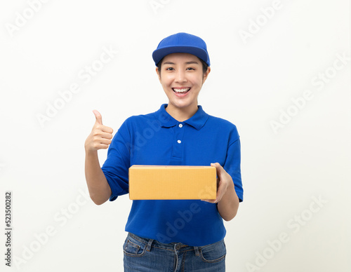 Happy delivery asian woman in blue uniform standing holding parcel cardboard box on isolated white background. Smiling female delivery sending box package service worker.