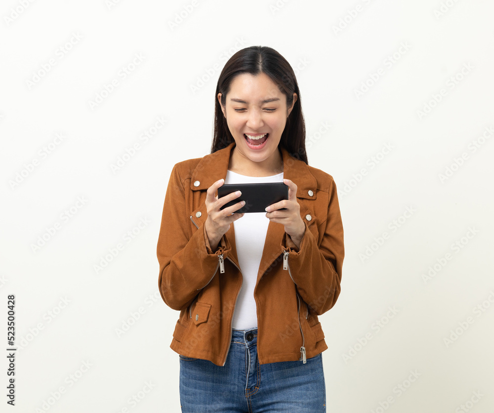 Excited Beautiful young asian women play mobile game and standing on isolated yellow background. Playing game on smartphone winning victory moment. Very enjoy and fun relax time Excited Beautiful young asian women play mobile game and standing on isolated yellow background. Playing game on smartphone winning victory moment. Very enjoy and fun relax time