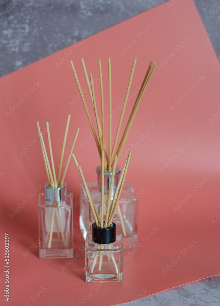 glass bottles of aromatic reed diffuser with wooden sticks on a pink background glass bottles of aromatic reed diffuser with wooden sticks on a pink background