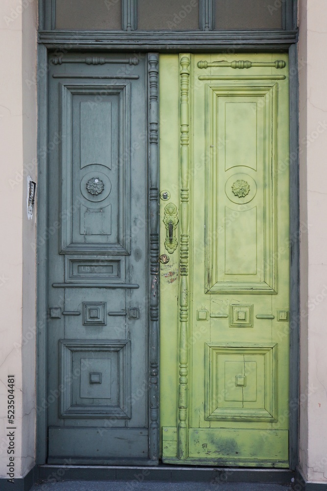 Decorative, wooden door in an old tenement house painted in shades of green