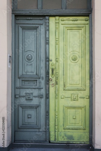 Decorative, wooden door in an old tenement house painted in shades of green
