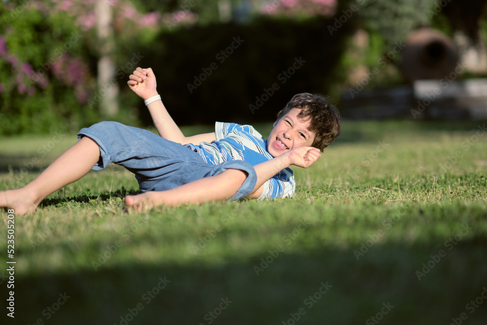boy preschooler somersaults on the grass on a hot summer day.