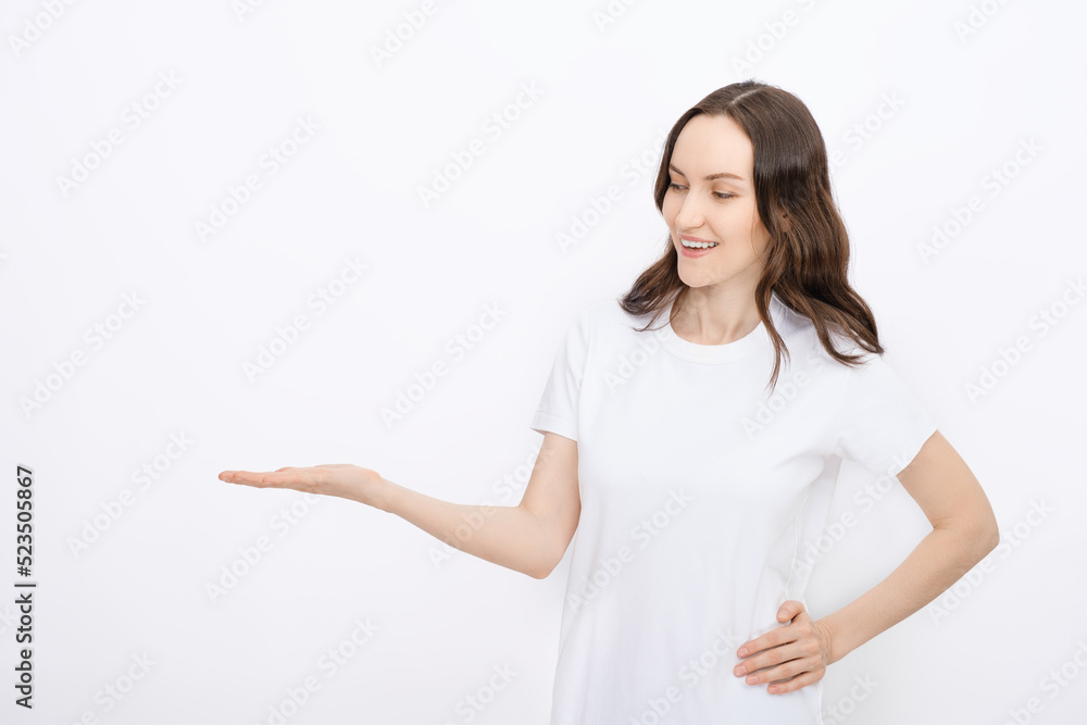 clean minimal portrait of smiling brunette woman in white T-shirt on white background holds bent arm for advertising goods, copy space, template clean minimal portrait of smiling brunette woman in white T-shirt on white background holds bent arm for advertising goods, copy space, template
