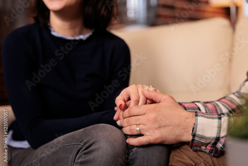 Husband and wife holding hands after solving marriage conflict with help from couselor at therapy session. Happy couple feeling good about relationship reconciliation in office.