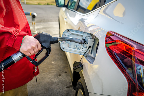 Male hand close-up refueling a white car. Higher oil prices