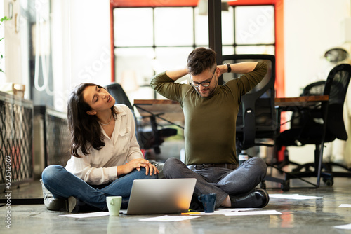 Colleagues in office. Businesswoman and businessman sitting on the floor. Colleagues working on the project