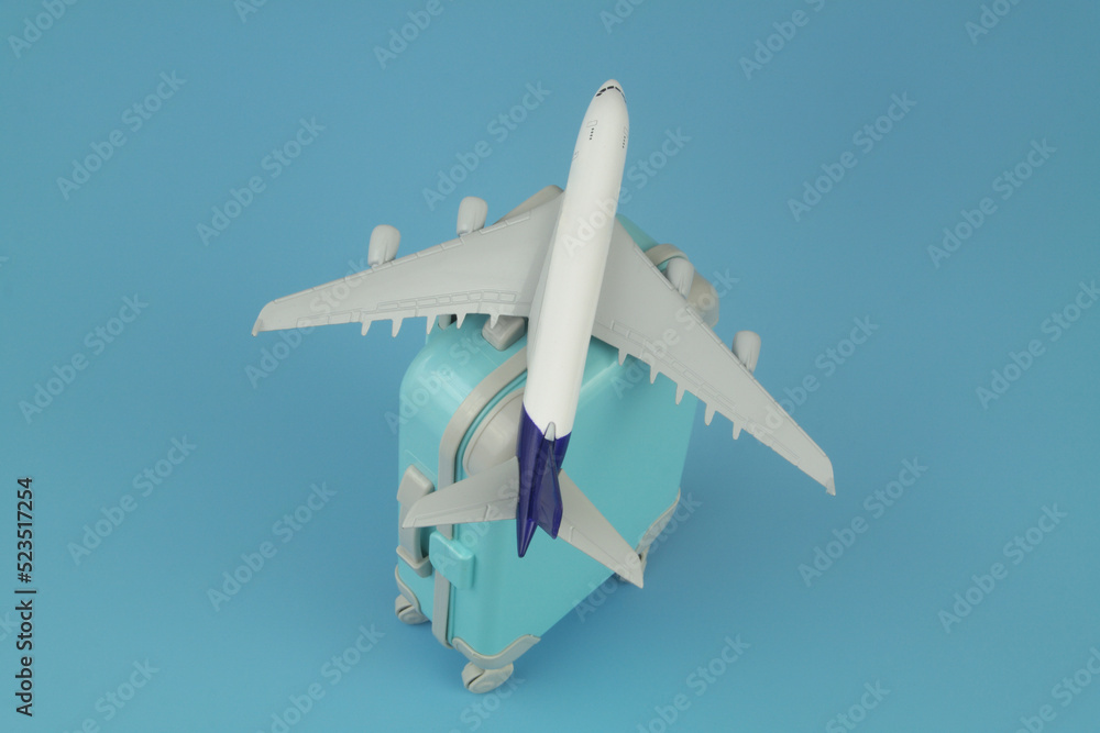 Airplane model with travel suitcase on blue background. Vacation and travel concept. Airplane model with travel suitcase on blue background. Vacation and travel concept.