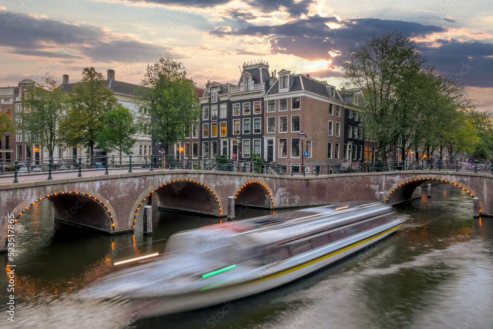 Tourist Boat on the Evening Amsterdam Canal with Bridges