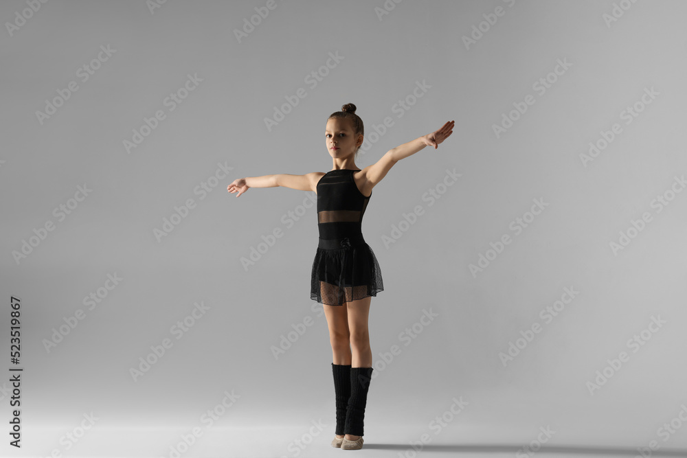 Cute little gymnast in stage clothes on white background