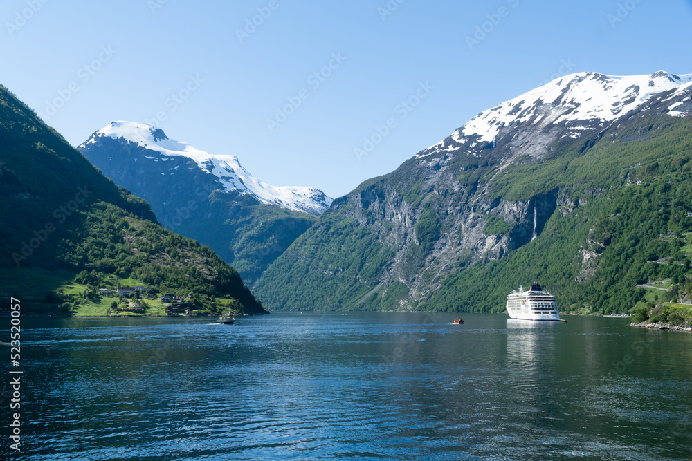 Geirangerfjord landscape with a cruise ship and snow-capped mountains in the background.