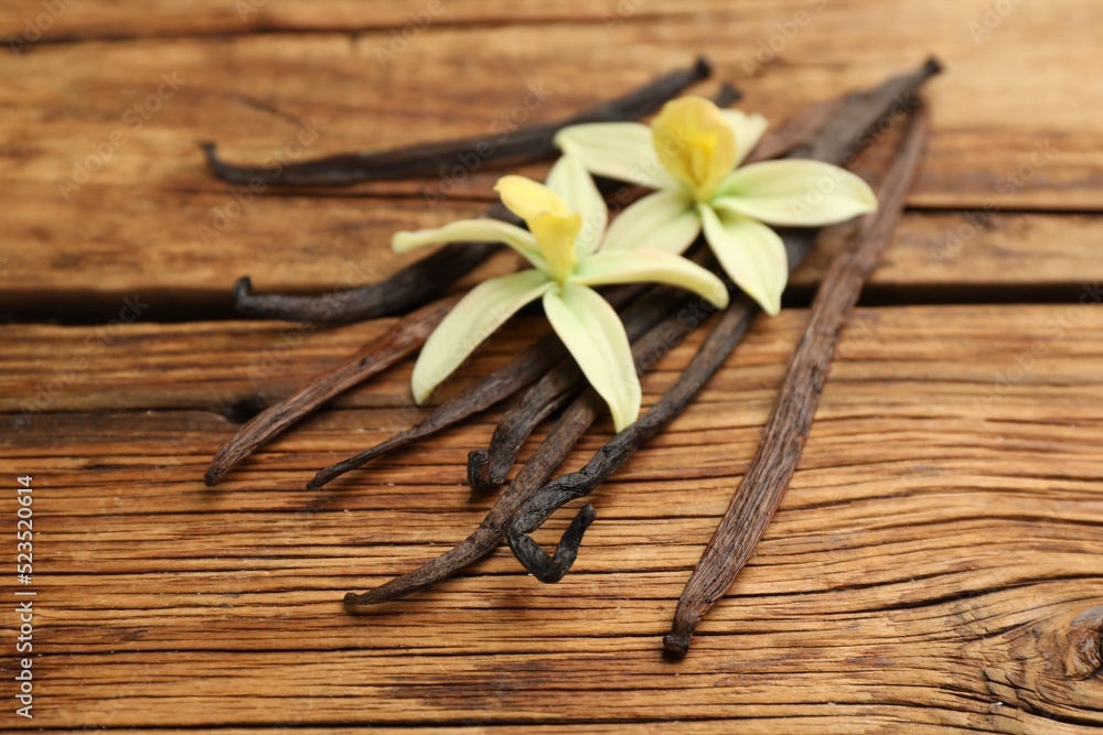 Aromatic vanilla sticks and flowers on wooden table, closeup Aromatic vanilla sticks and flowers on wooden table, closeup