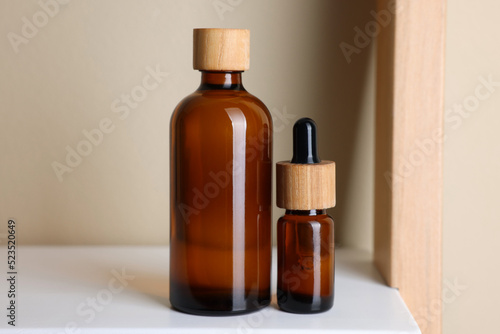 Glass bottles of cosmetic products on white shelf