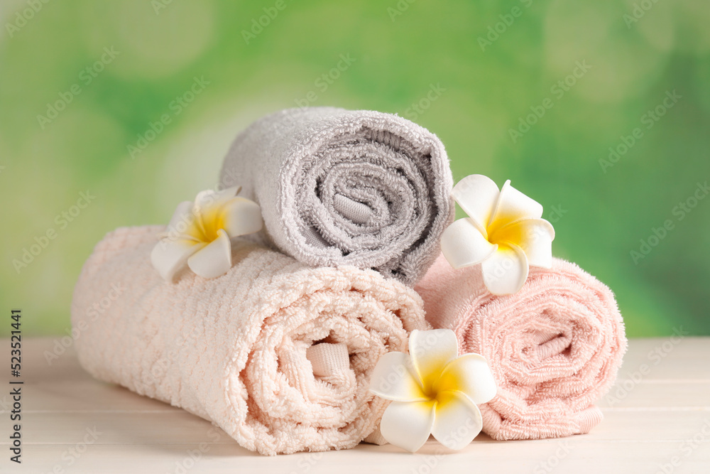 Soft folded towels and plumeria flowers on white wooden table Soft folded towels and plumeria flowers on white wooden table