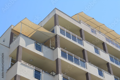 Fotografie, Tablou Exterior of residential building with balconies against blue sky, low angle view